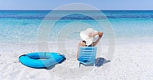 girl with white straw hat relaxes in front of the sea photo